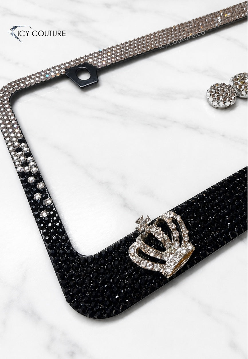 Close-up detail of a black and clear ombre crystal license plate frame by ICY Couture with 3D rhinestone crown accents and matching crystal screw caps for luxury car styling.
