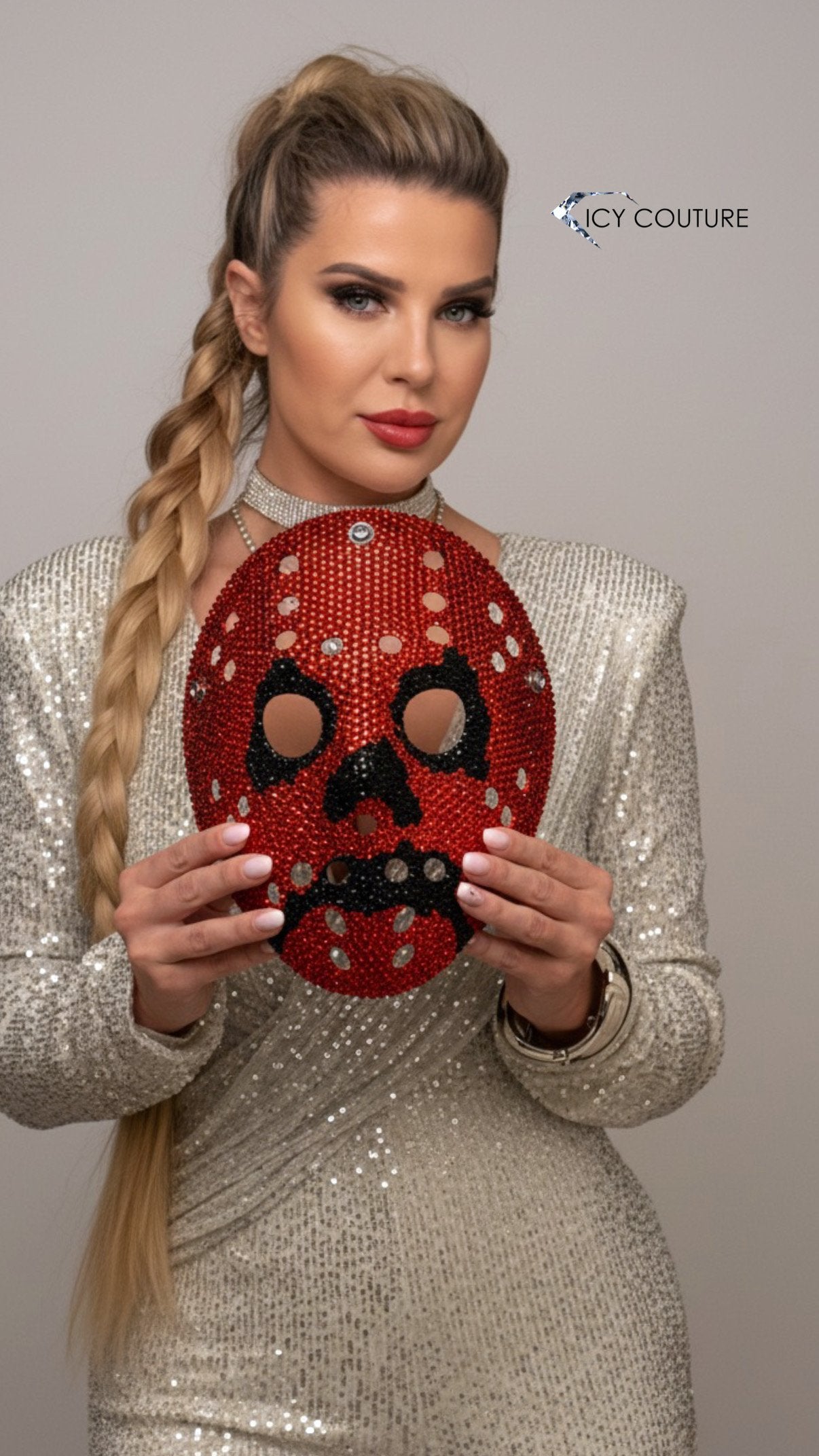 Nikita Chistova holding an orange and black crystallized hockey mask with rhinestones.