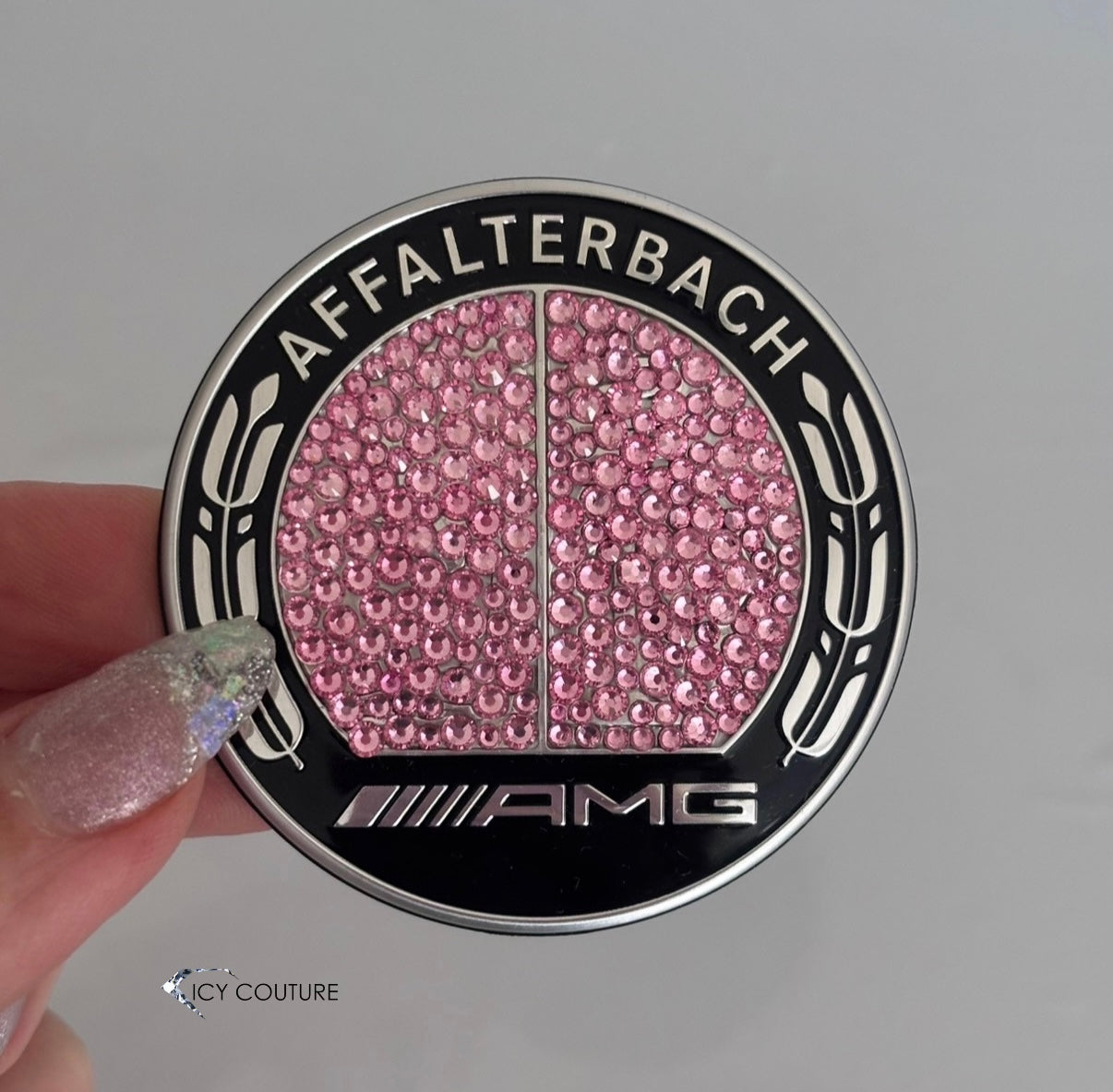 Pink Mercedes  Crystal Hood Cap Emblem  Affalterbach AMG text on a black background